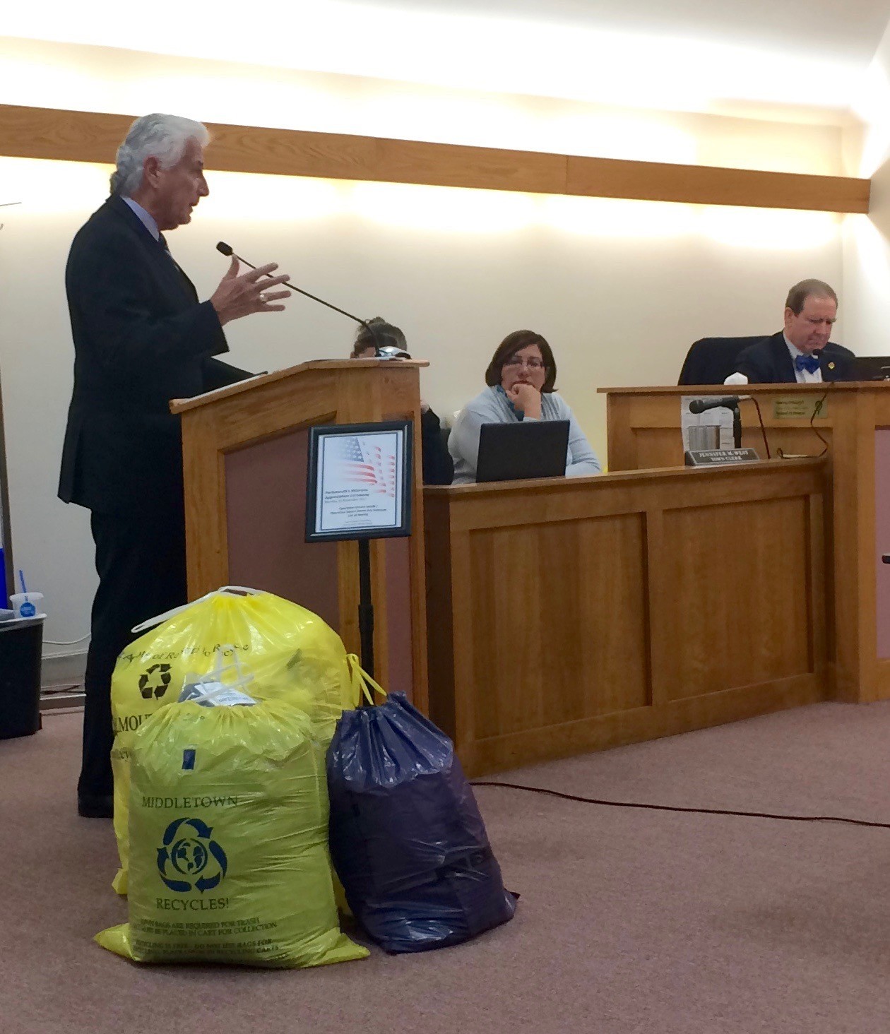 Bob Moylan, former public works commission in Worcester, tells the Town Council how a pay-as-you-throw system benefitted his city after it was adopted 22 years ago. On the floor are three examples of bags Portsmouth residents participating in the system will use.