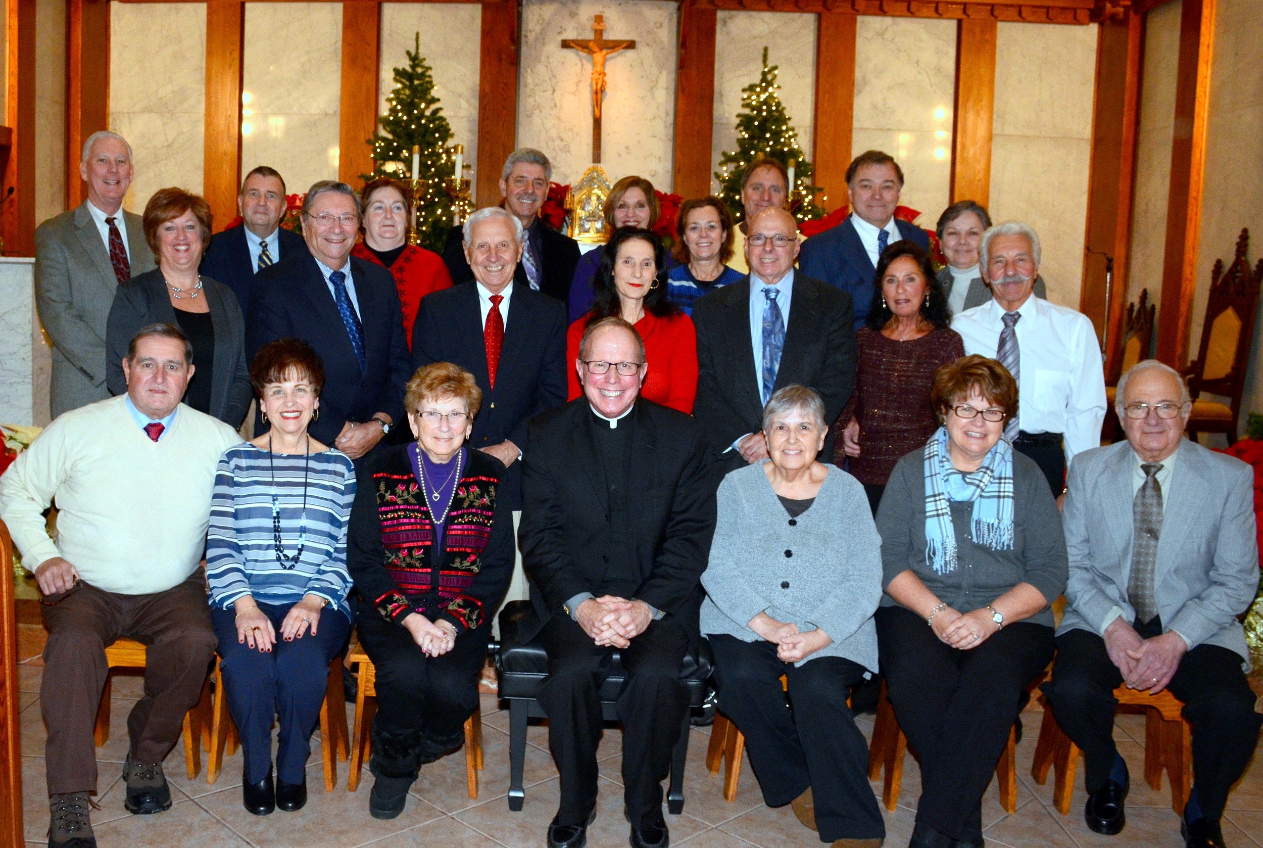 Past Chief Marshals of the Our Lady of Mt. Carmel Church Feast gathered for a group photo (with pastor Henry P. Zinno Jr. (seated front row center) Saturday as part of the church's 100th anniversary celebration, which officially began this past weekend. They include front row left-right Manny Pasqual, Theresa Pasqual, Gloria Pasqual, Madeline Grimo, Betty Vendituoli, and Frank Vaccaro. Second row left-right are Donna McKenna, Richard Carlone, Joseph Caromile, Caroline Campagna, Vincent Campagna, Joan Castigliego, and Nick Castigliego. Back row left- right are Bob McKenna, Jeff Steadman, Alisa Steadman, Paul Viveiros, Carol Viveiros, Tammie Delmage, Bill Delmage, Bob Ruginis, and Kathy Ruginis.