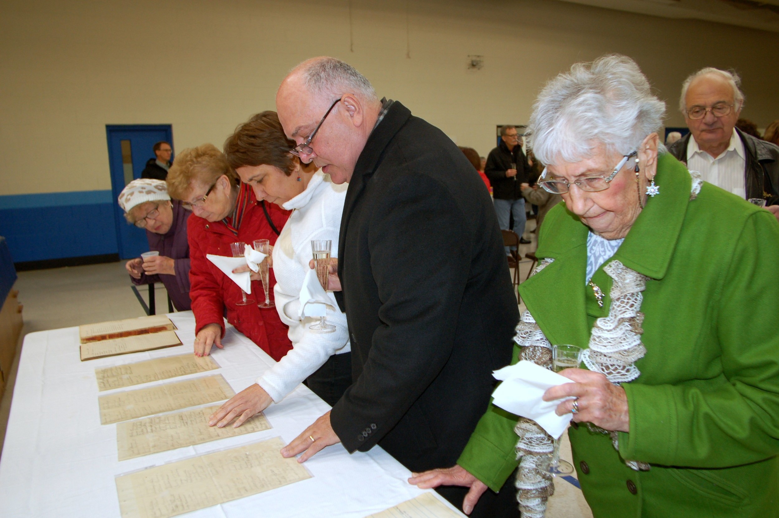 Our Lady of Mt. Carmel parishioners look over original church documents, which were on display Sunday at reception in the Monsignor John W. Lolio Hall.