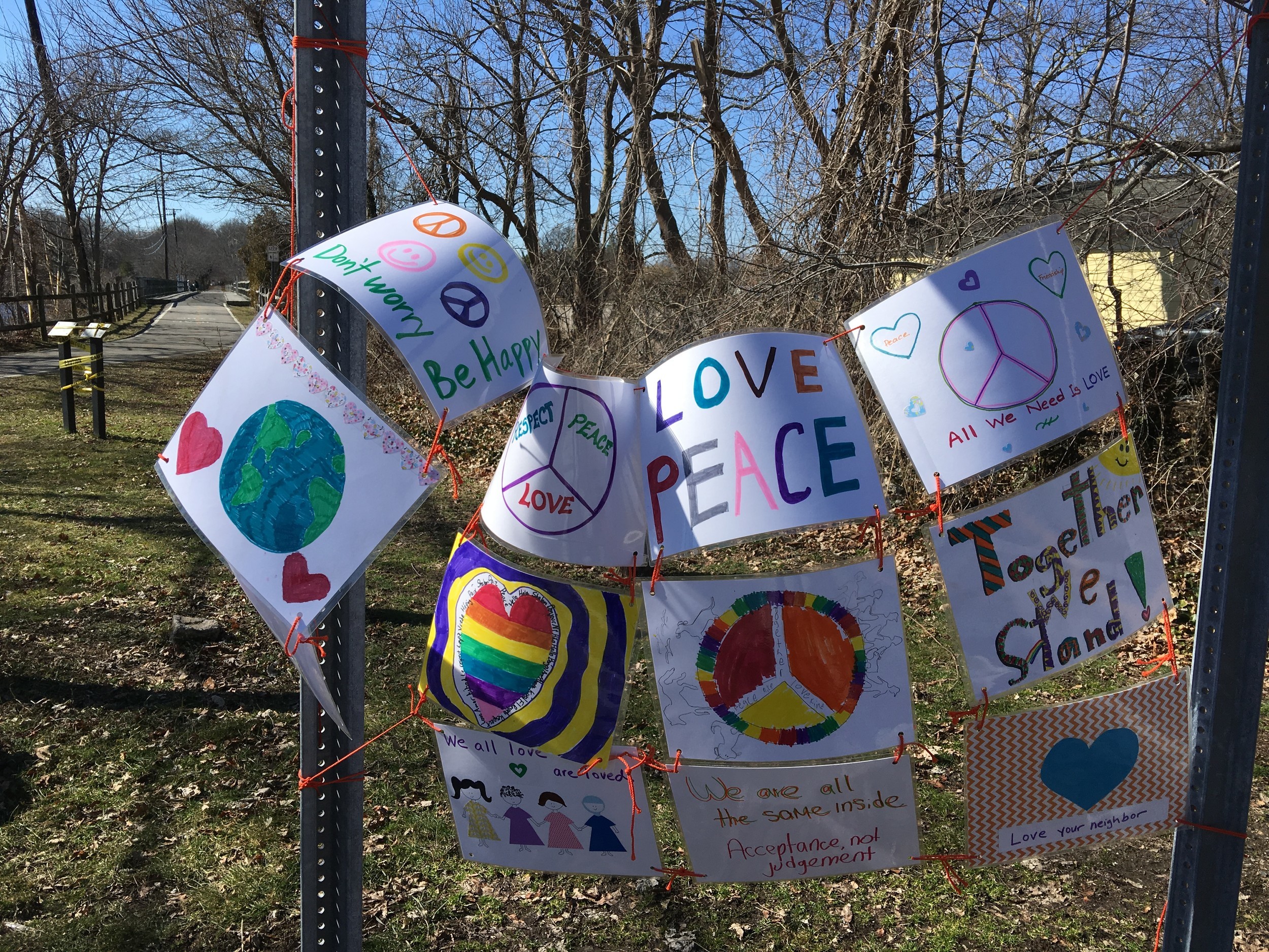 Signs sharing messages of peace, love and unity greet people near the intersection of New Meadow Road and the bike path.