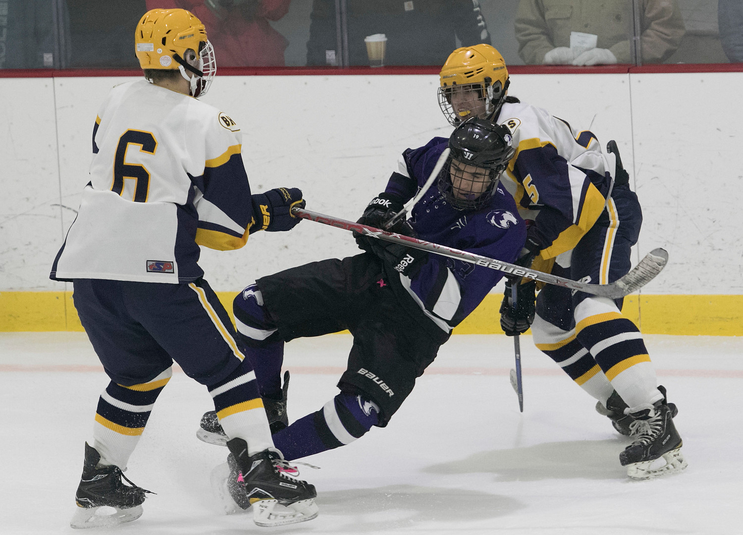 Senior center Kyrik Cordeiro is helped to the ice by a pair of Barrington defenders.